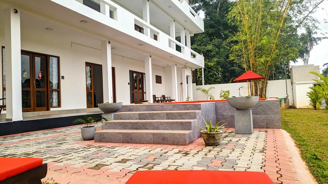 White villa exterior beside the red pool and tropical garden