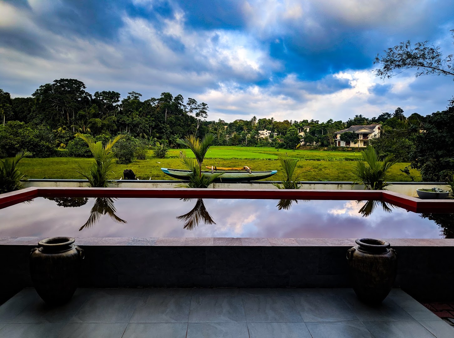 Red pool reflecting a blue sky beside rice fields
